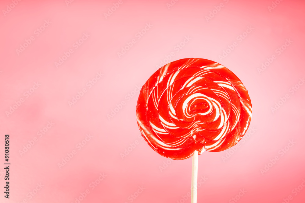 Giant spiral lollipop on pink pastel background