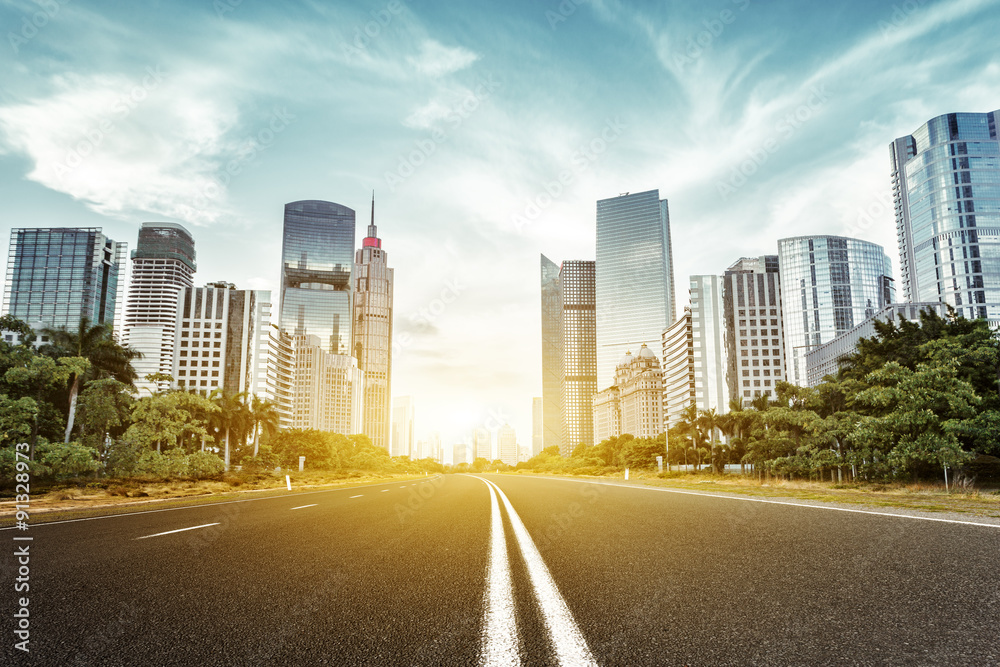 asphalt road and skyscrapers under sunbeam