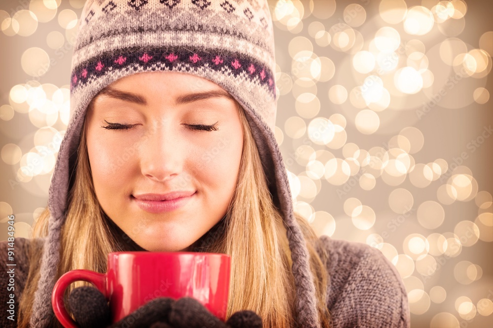 Composite image of happy blonde in winter clothes holding mug