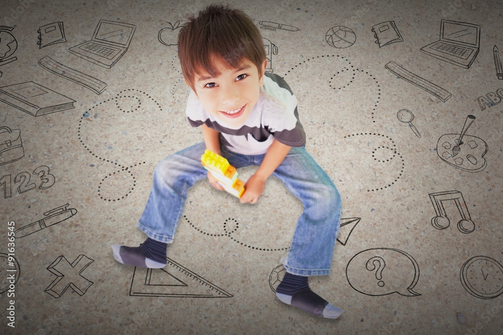 Composite image of cute boy sitting with building blocks