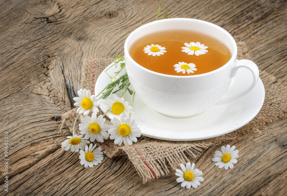 Cup of tea and chamomiles on wooden background