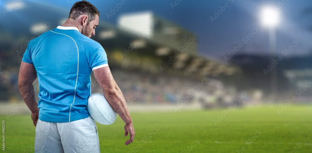 Composite image of rugby player standing with ball