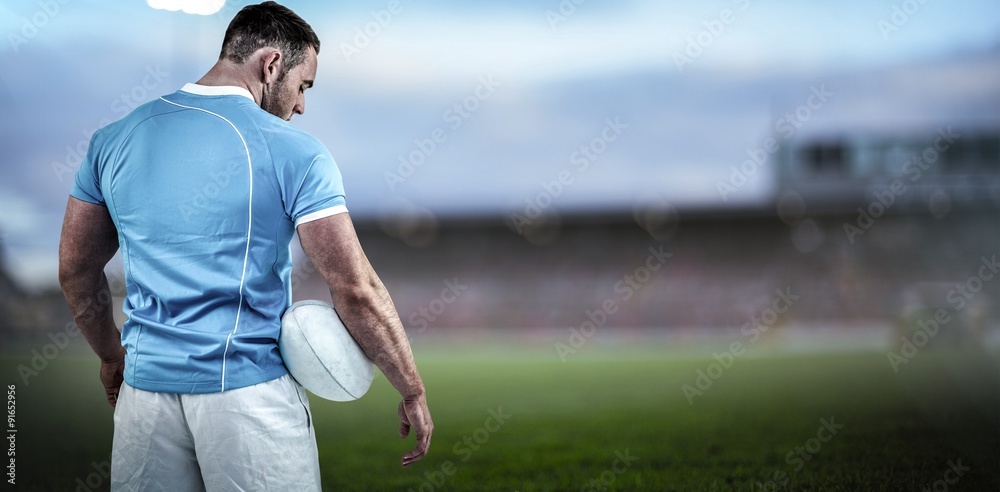 Composite image of rugby player standing with ball