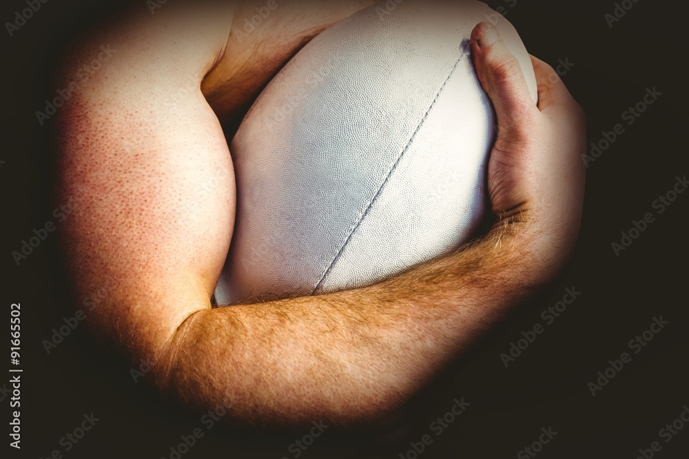 Shirtless rugby player holding ball