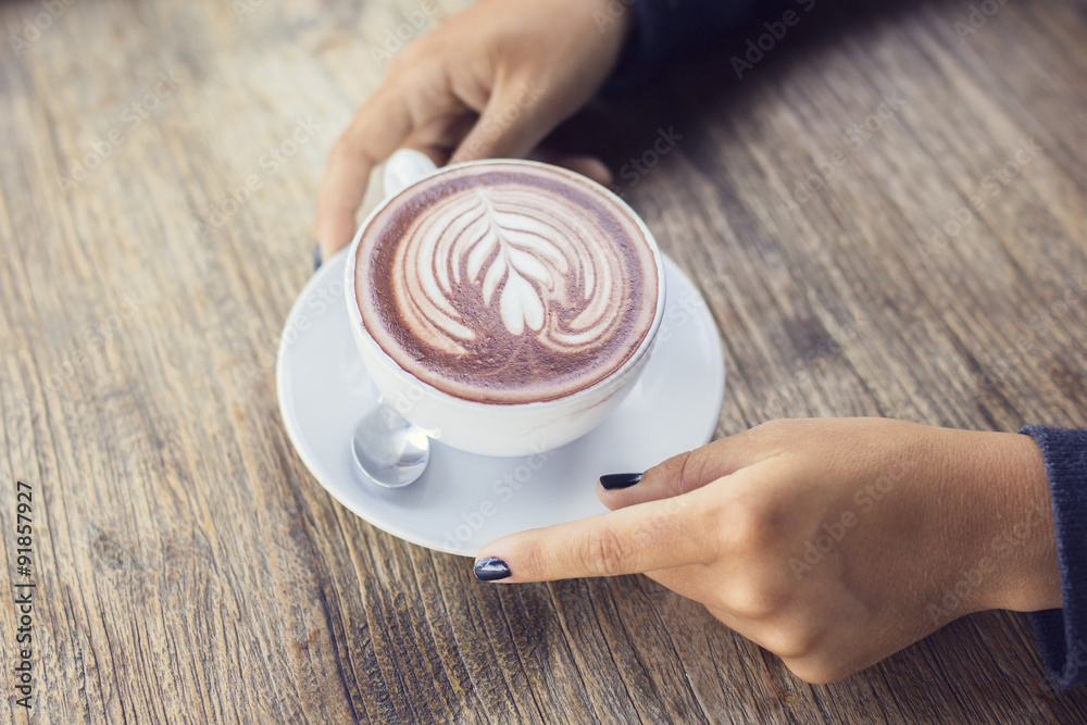 womans hands with a cup of cappuccino