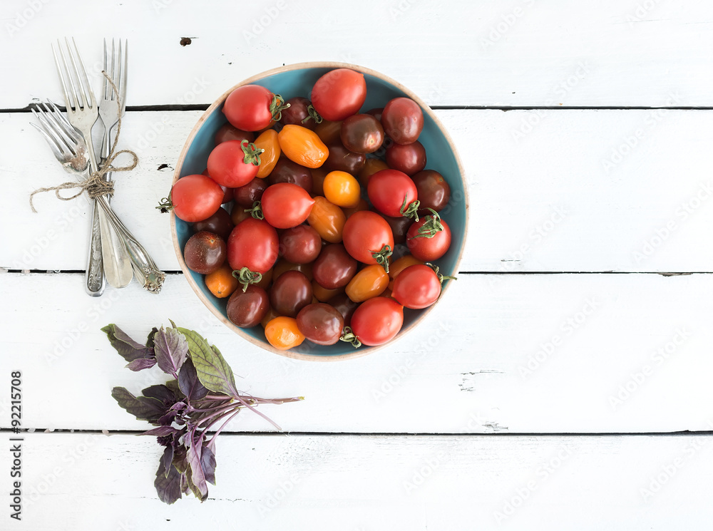 Cherry tomatoes in blue ceramic bowl, vintage silverware and