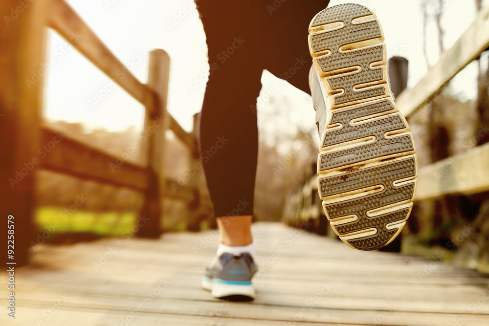 Woman jogging across a country bridge at sunset