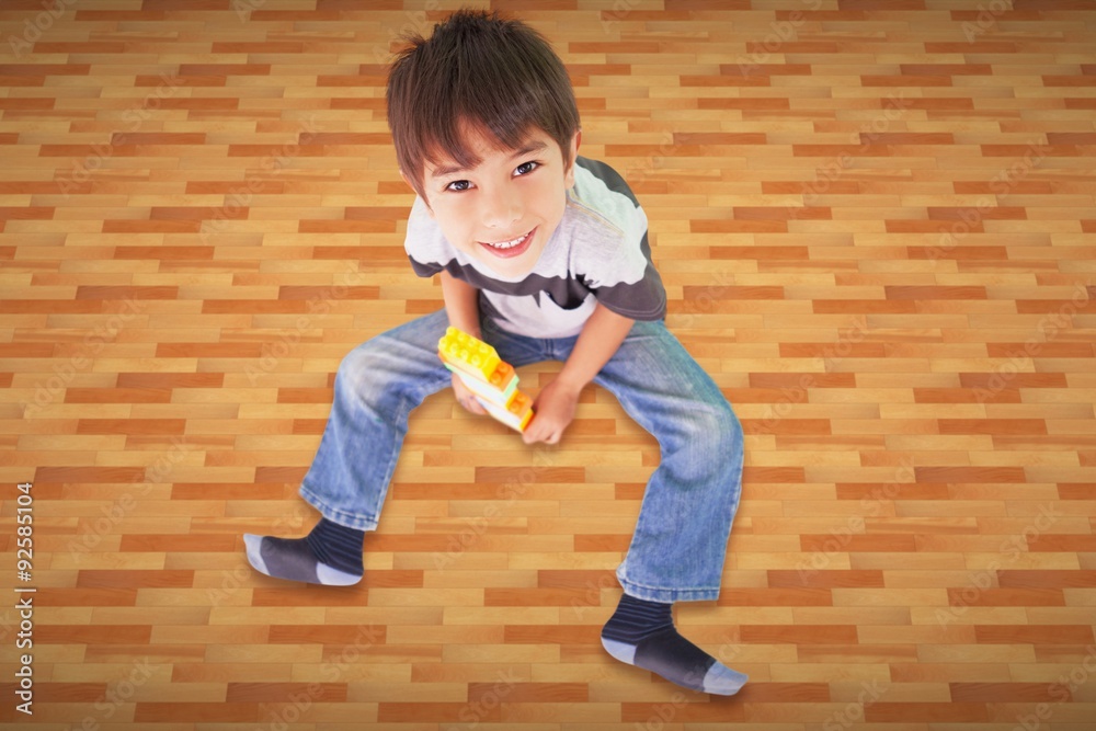 Composite image of cute boy sitting with building blocks