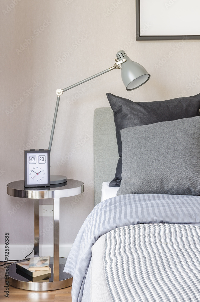 modern grey lamp with alarm clock on side table in bedroom