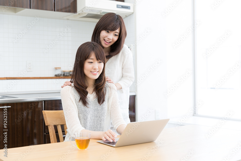 asian women using laptop in the kitchen