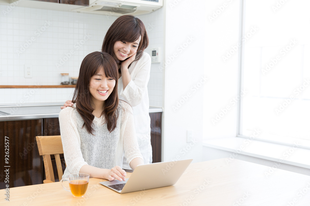 asian women using laptop in the kitchen