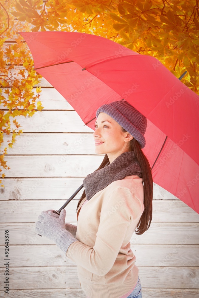 Composite image of smiling brunette holding red umbrella