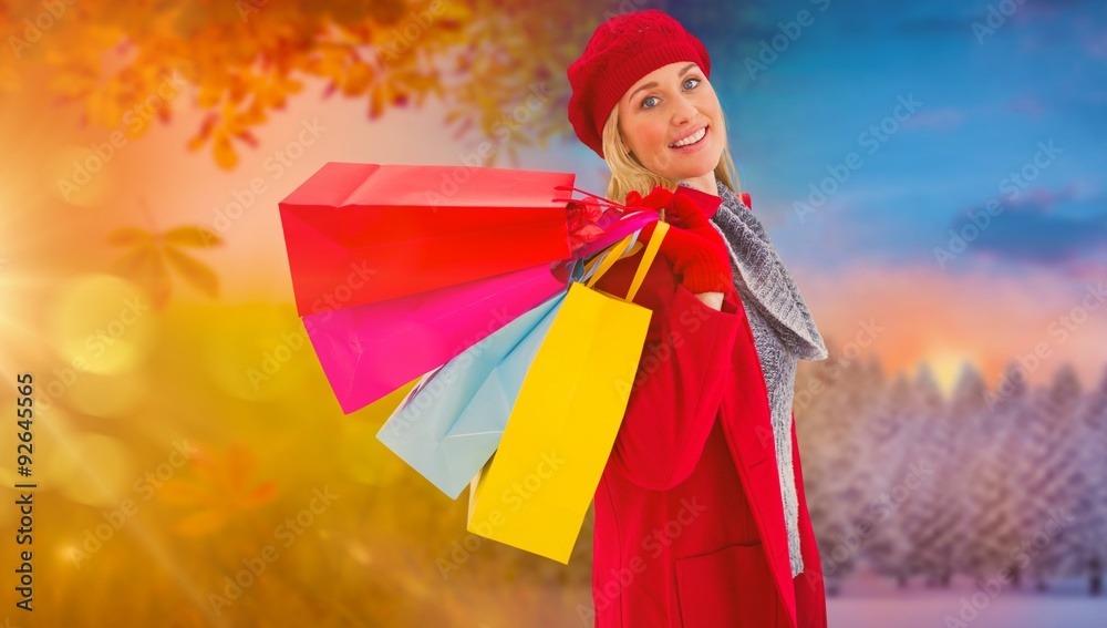 Composite image of blonde in winter clothes holding shopping bag