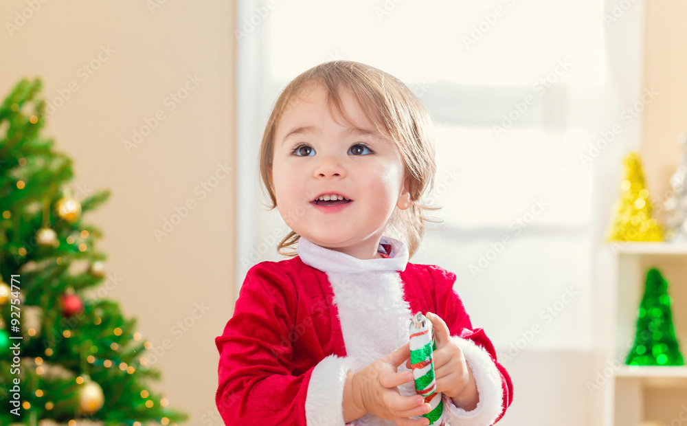 Little toddler girl receiving a candy cane from Santa Claus