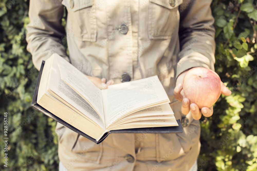 Girl reading a book and carrying an apple