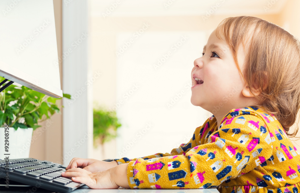 Happy little girl having fun using her computer