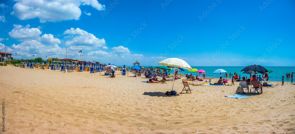 Beautiful vacation beach with beach chairs and sun shades on a sunny day at Lido di Metaponto, Basil