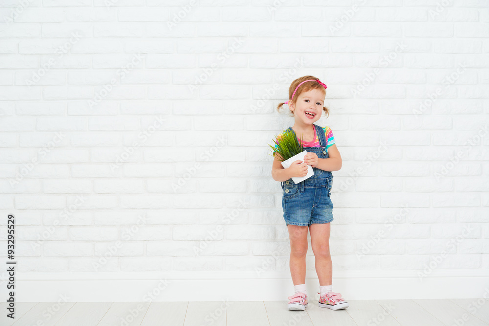 happy child girl laughing and holding pot with potted plant near