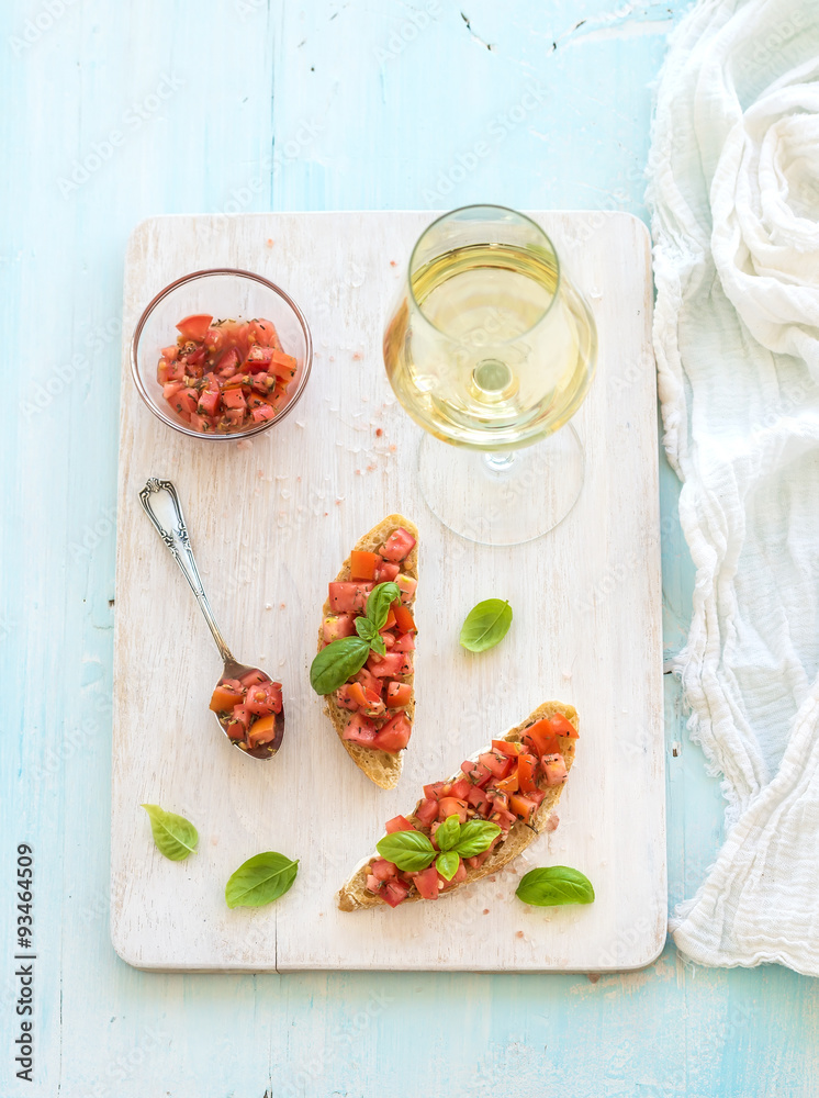 Tomato and basil bruschetta sandwich on white wooden serving