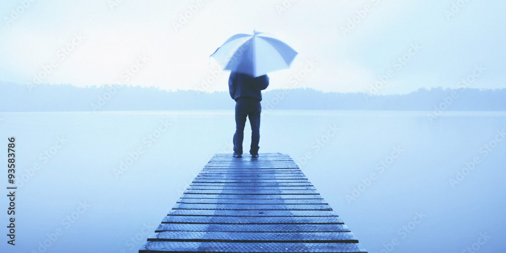 Man Holding an Umbrella on a Jetty by Tranquil Lake Concept