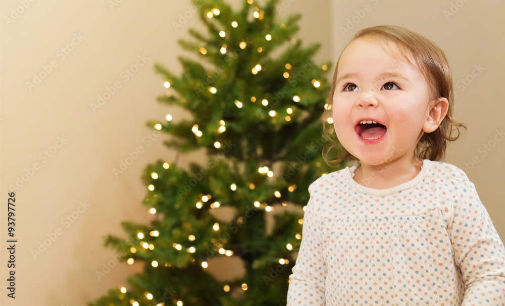 Cheerful girl smiling in front of the Christmas tree