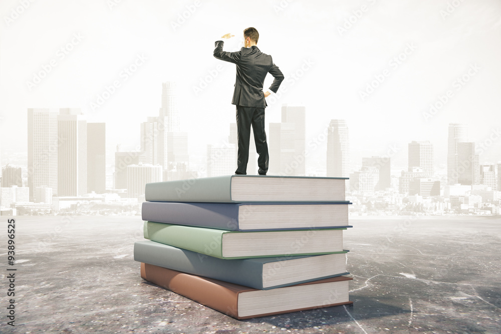 Businessman standing on a pile of books, learning concept