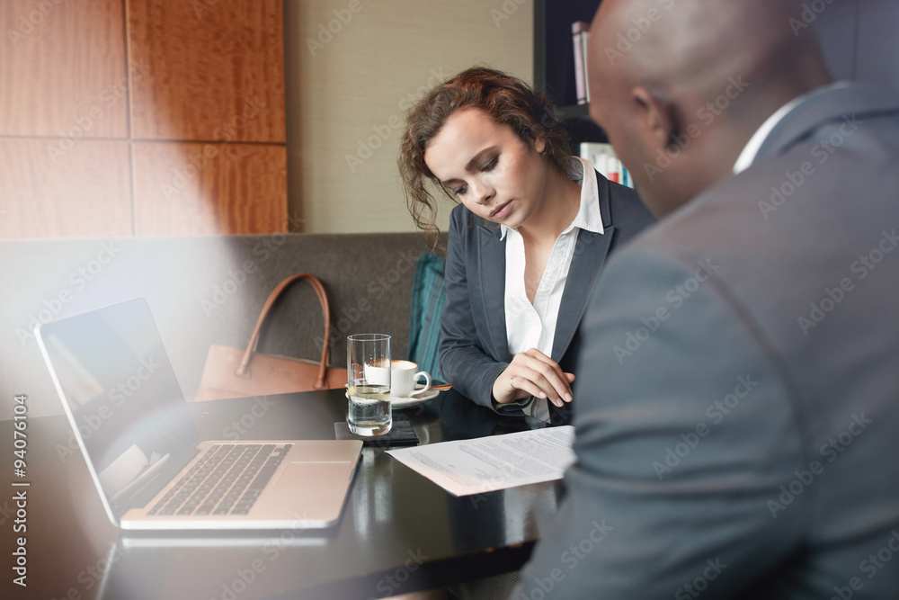 Business people discussing paperwork at cafe table