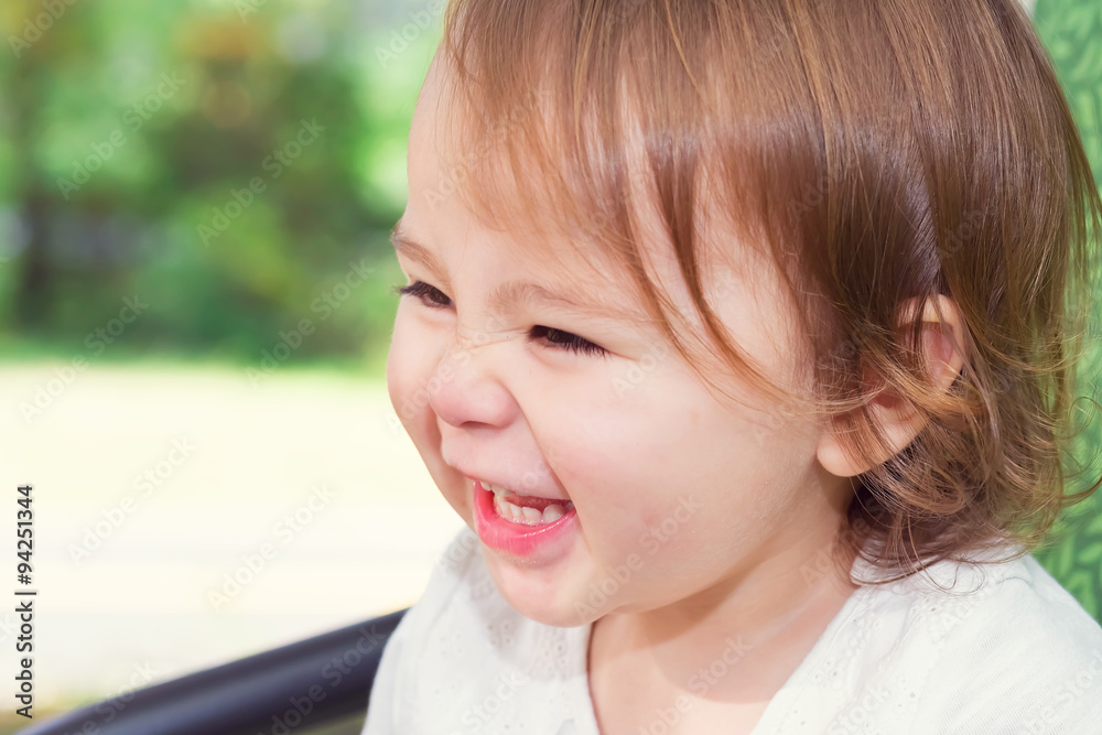 Happy toddler girl laughing while playing on a swing