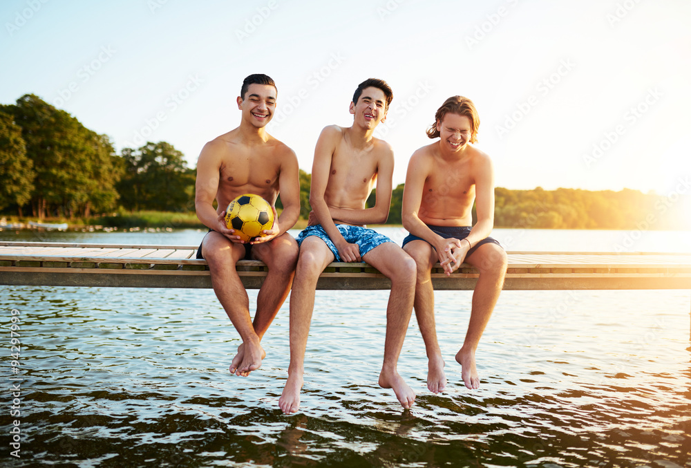 Three relaxed young teenage boys at a lake