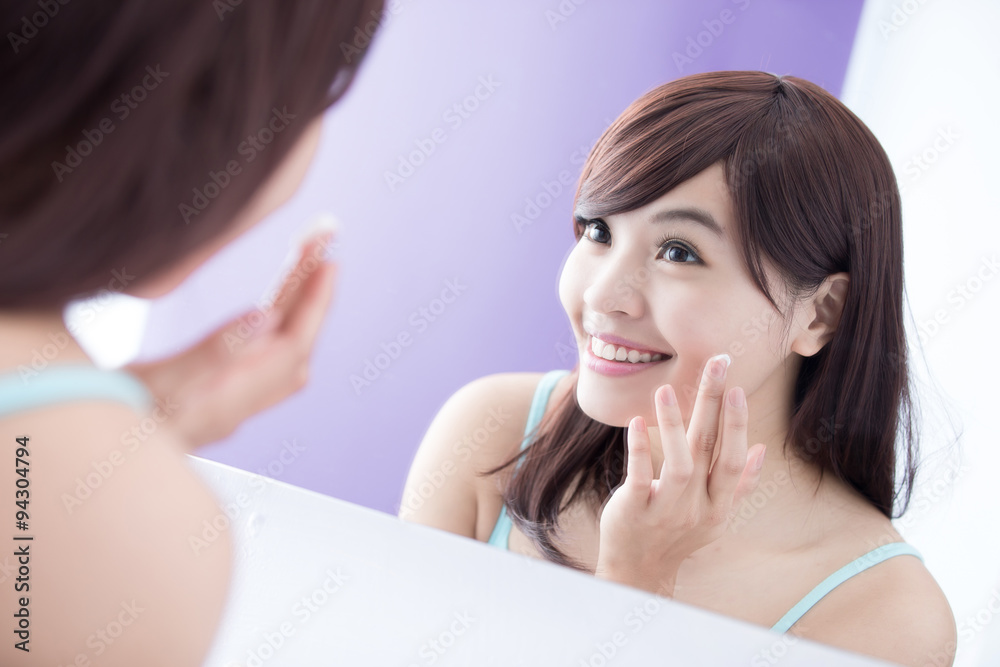 Smile woman applying moisturizer cream