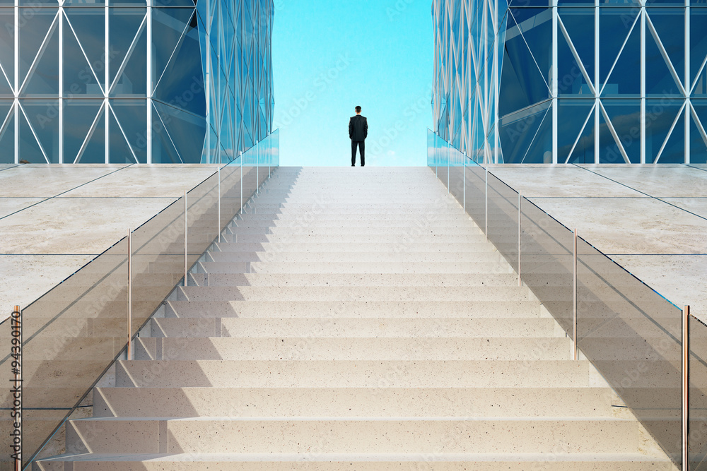 Businessman standing on top of the stairs near the modern busine