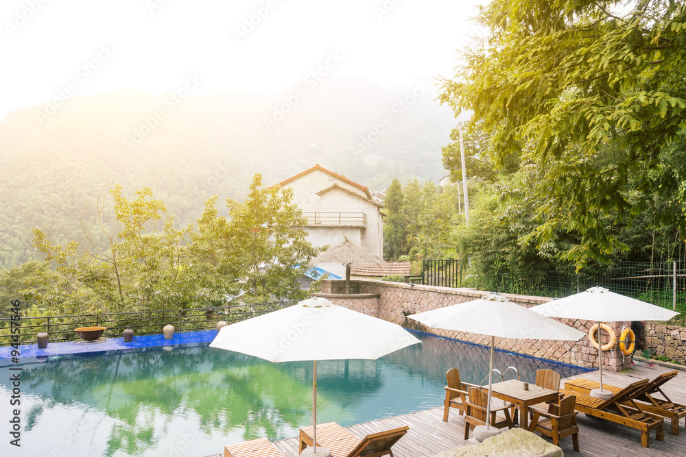 Umbrella chair in hotel pool resort with sunset