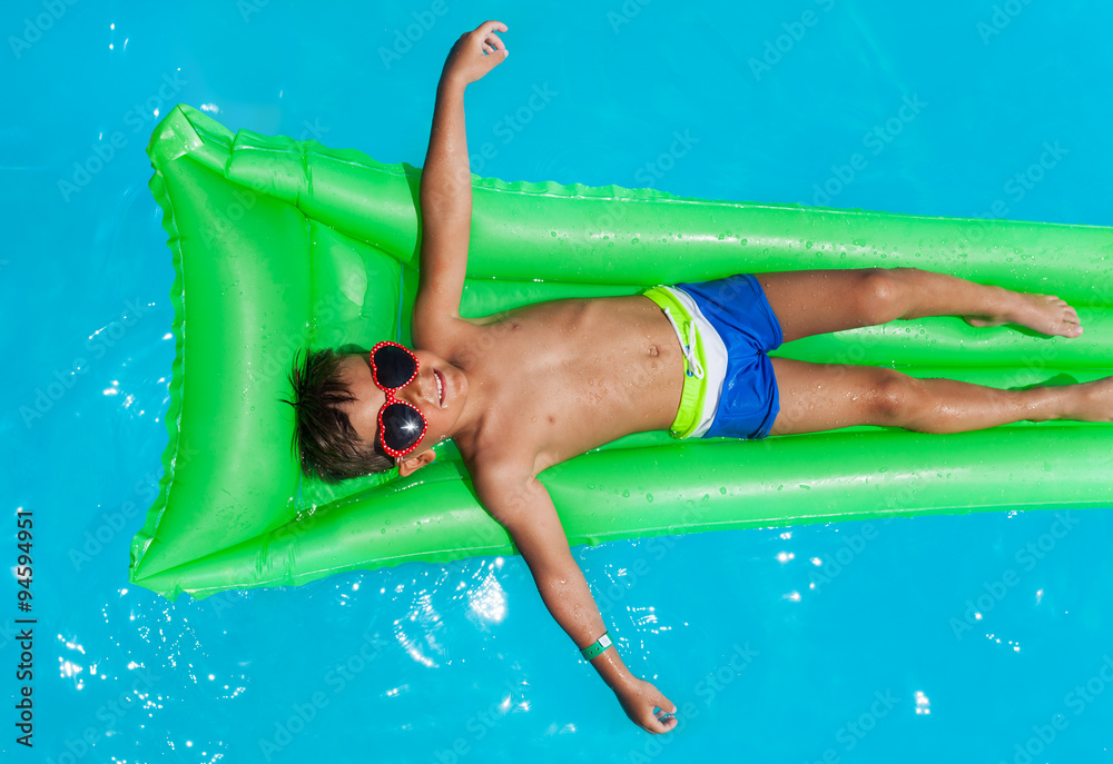 Boy wearing sunglasses relaxing on mattress