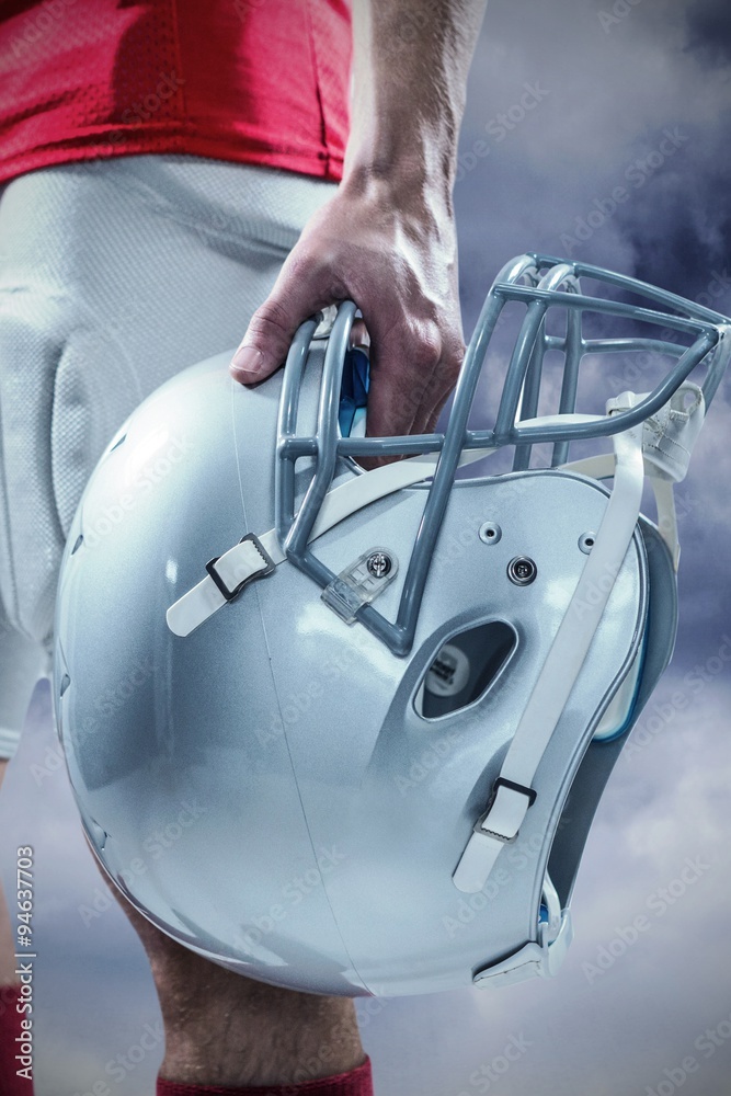 Composite image of helmet hold by american football player