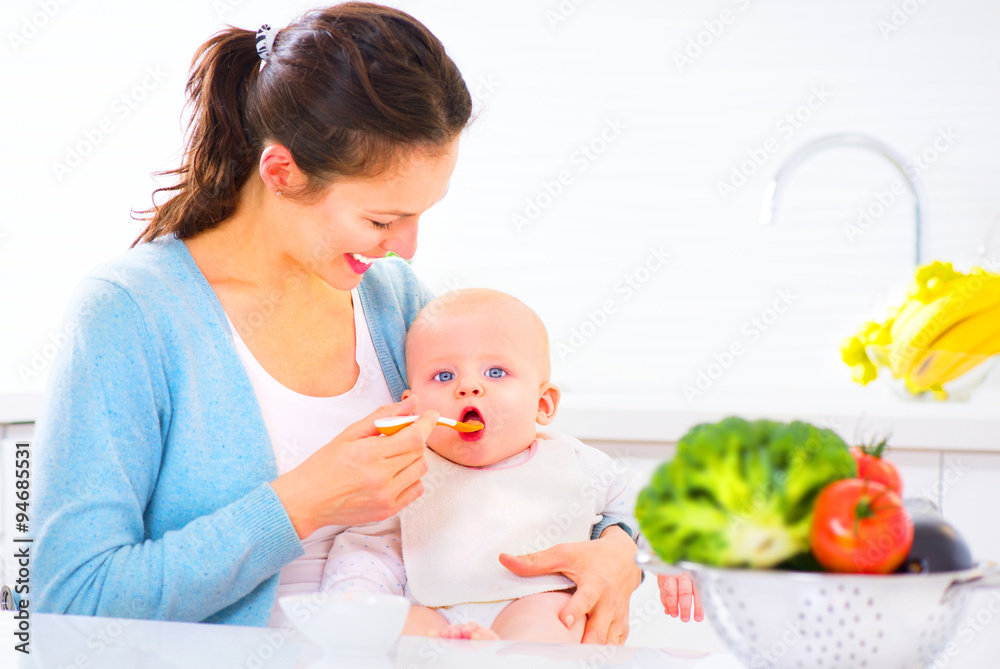 Mother feeding her baby girl with a spoon. Baby food