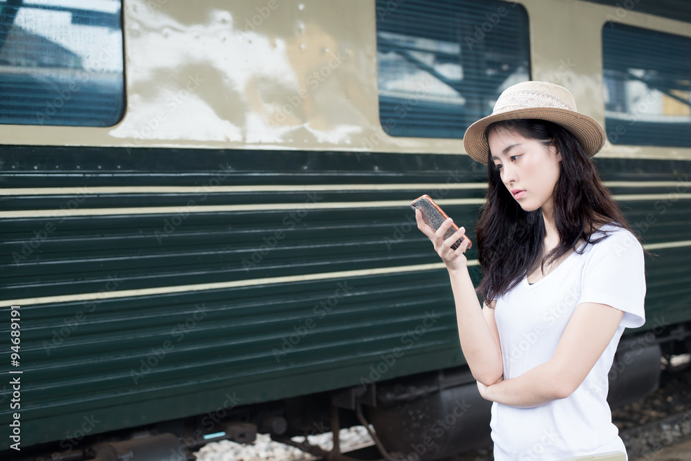 亚洲女子在火车站用智能手机发短信