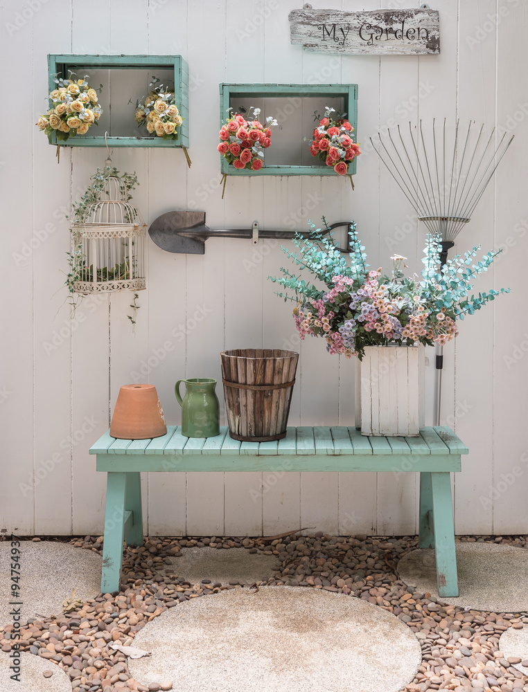 flower on green bench with white wood panel wall