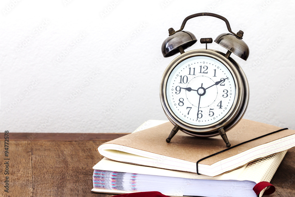 a vintage alarm clock  and books on wooden table with copy space