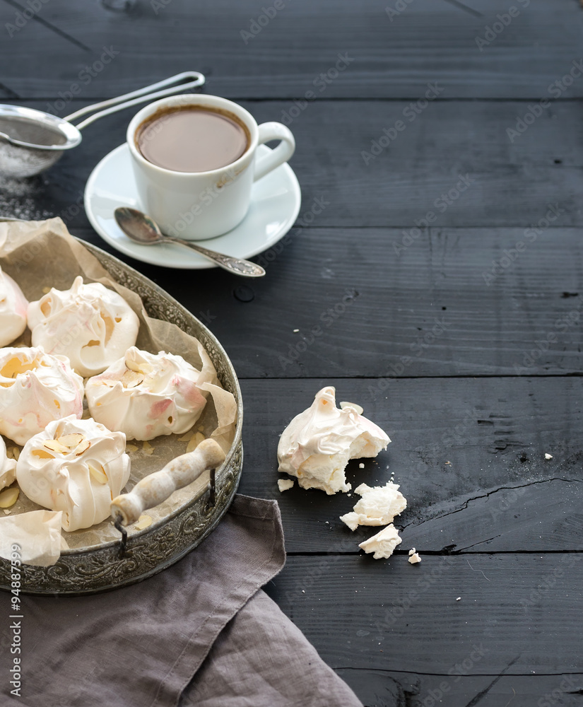 Almond meringues with cup of coffee on black rustic wooden table, top view