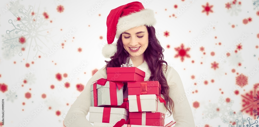 Composite image of festive brunette holding pile of gifts