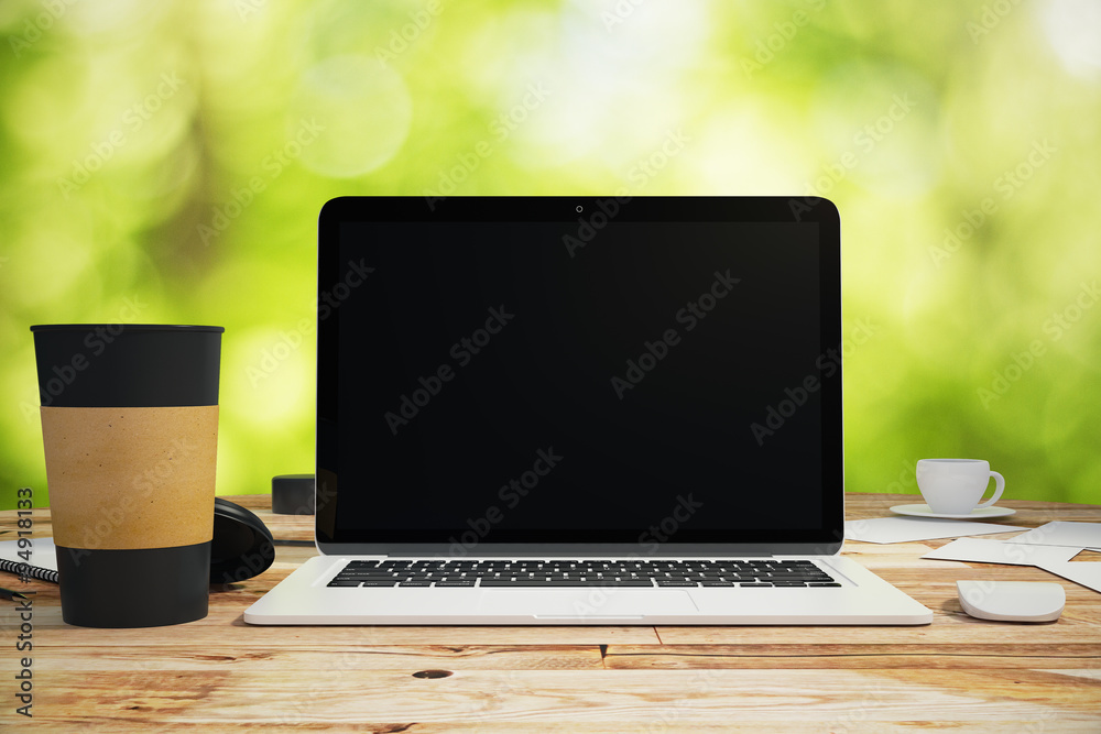 Blank screen of laptop with cup of coffee on the wooden table ou