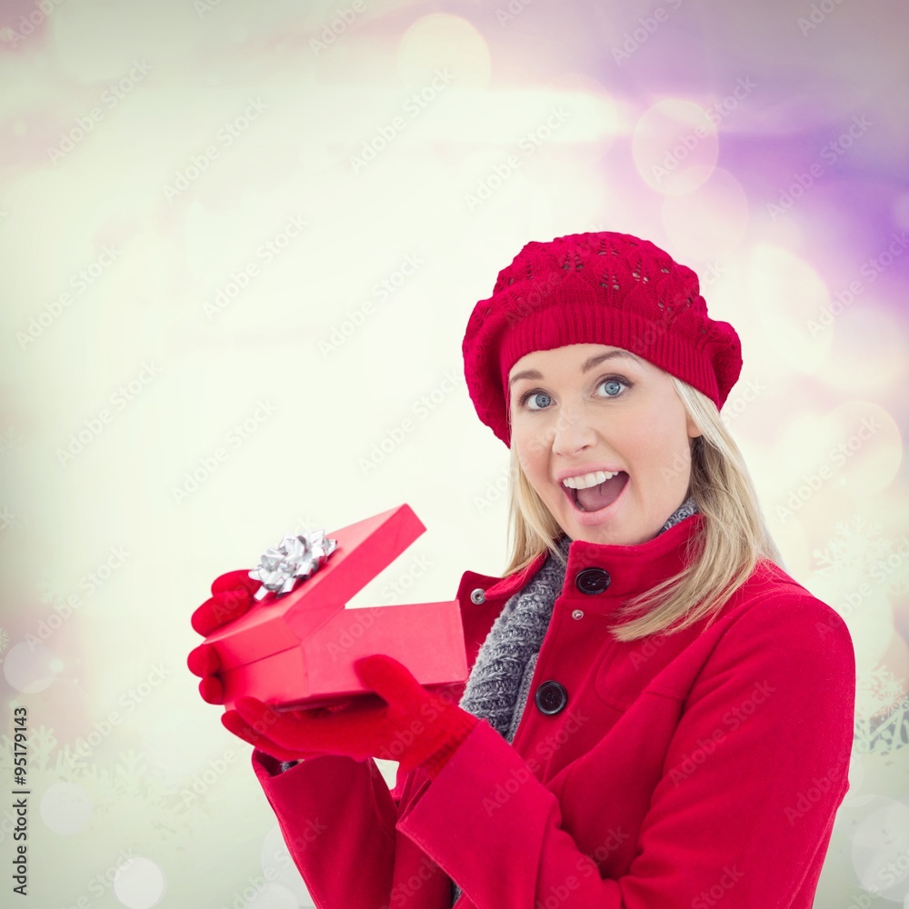 Composite image of festive blonde holding red gift 