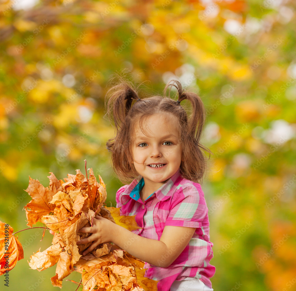 Happy girl with pile of autumn orange leaves