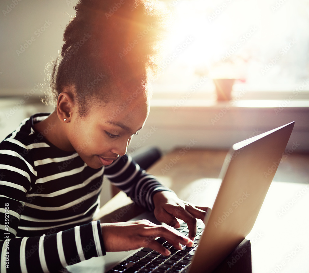 young girl typing on a laptop