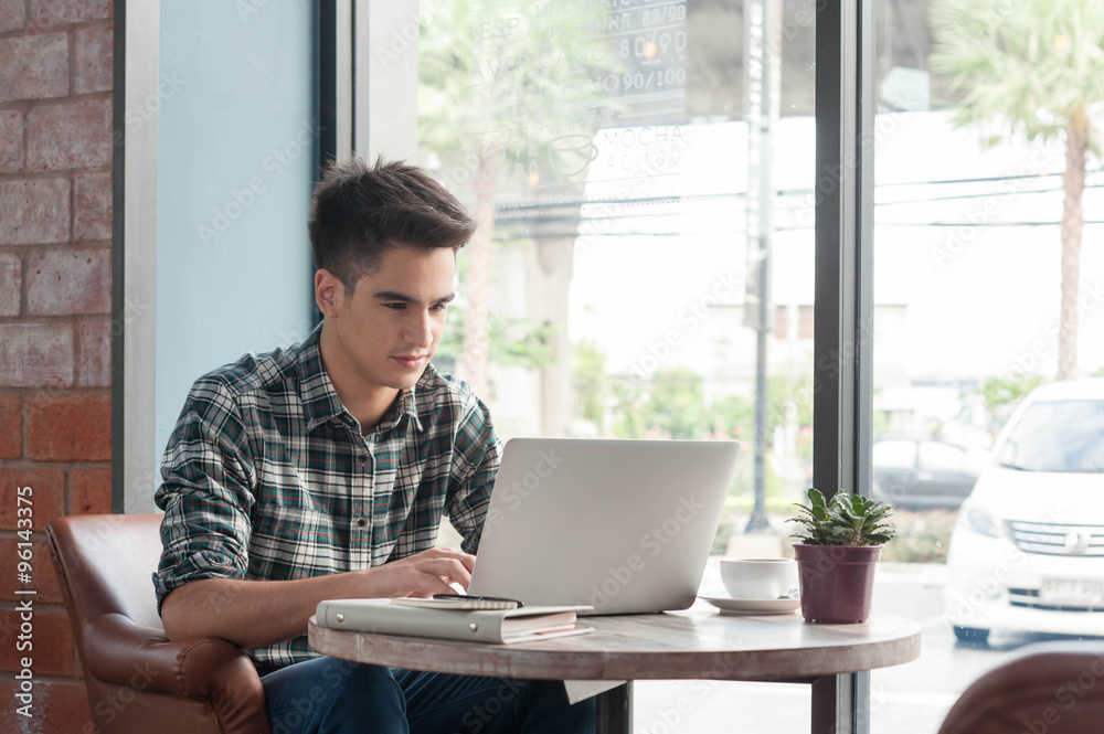 Businessman using laptop with tablet and pen on wooden table in