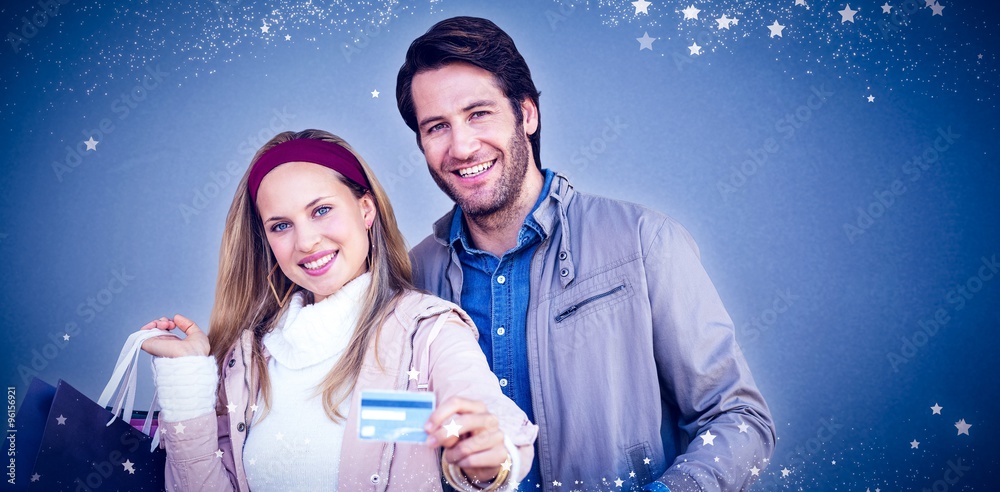 Smiling couple with shopping bags showing credit card