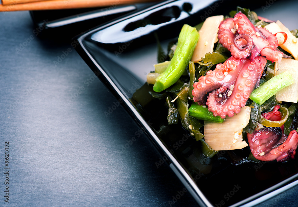 Japanese salad with octopus and ginger. Seafood over black background