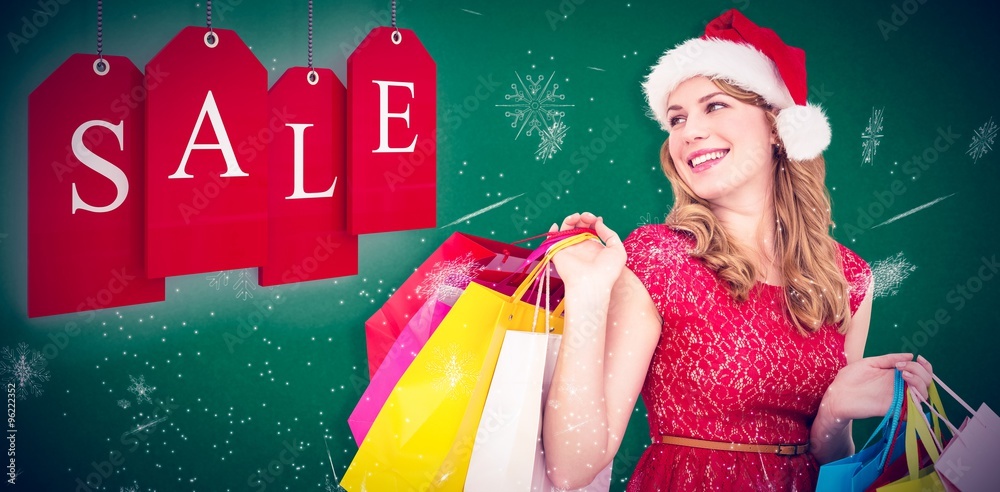 Smiling blonde in santa hat holding shopping bags