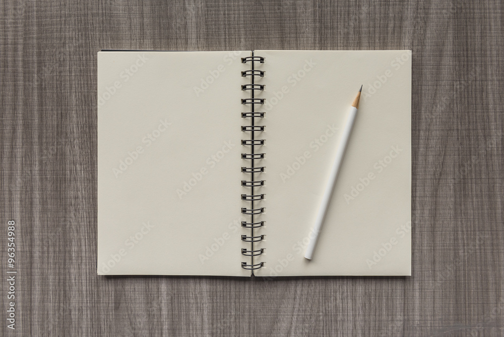 white pencil with blank notebook