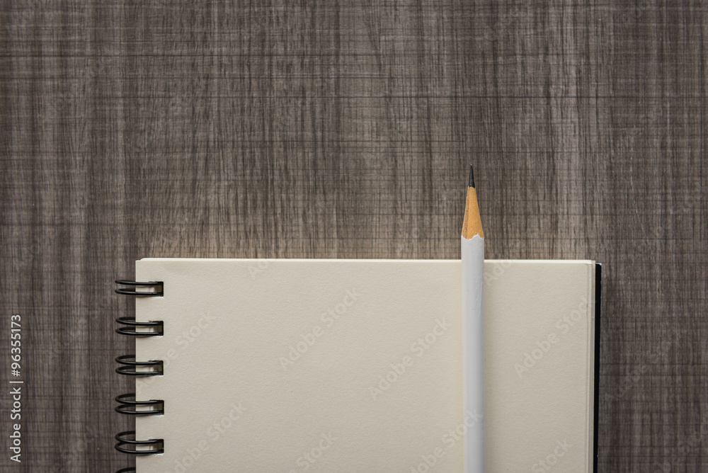 white pencil with blank notebook